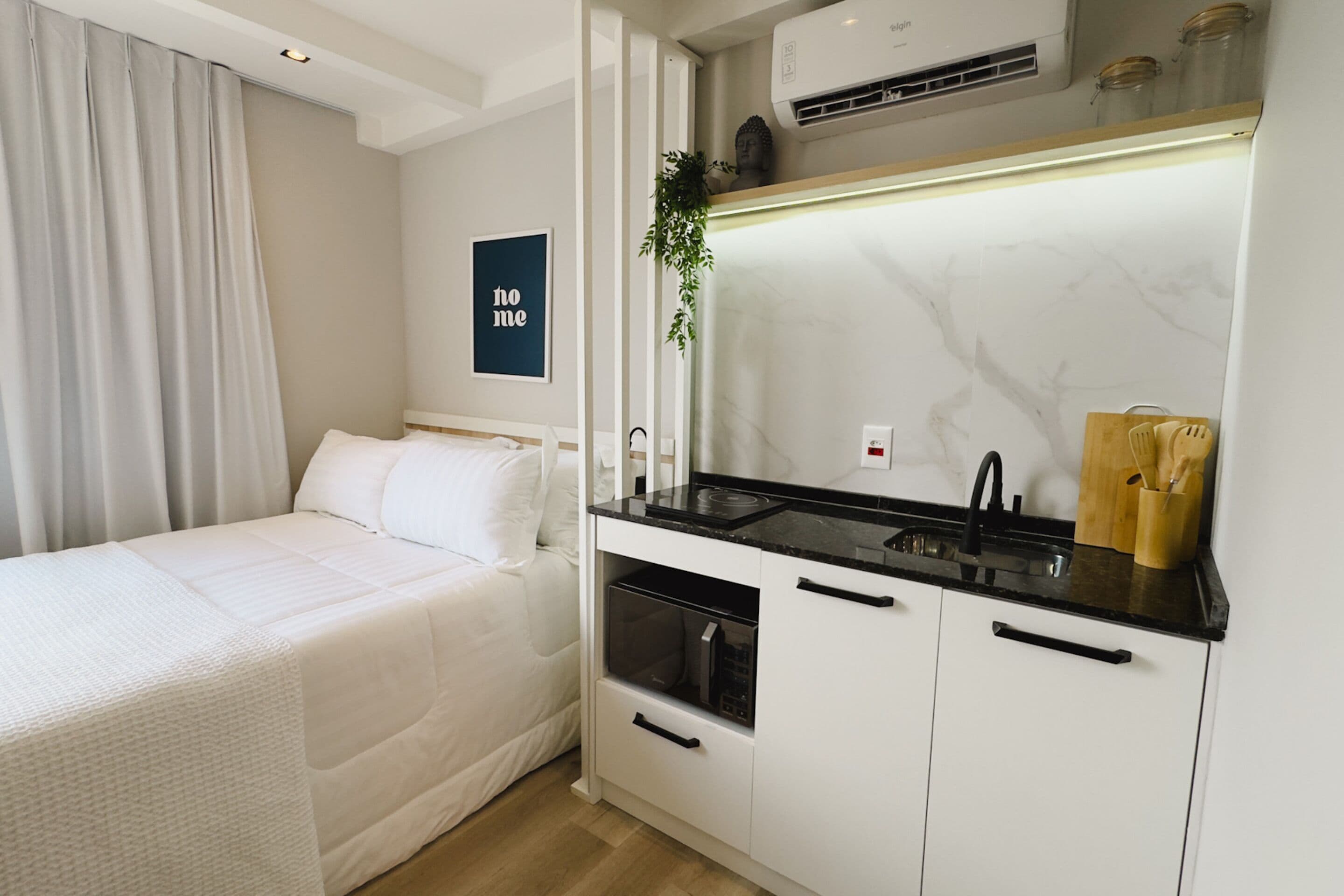 Une chambre compacte comprenant un lit, une petite kitchenette équipée d’un four à micro-ondes et un évier.