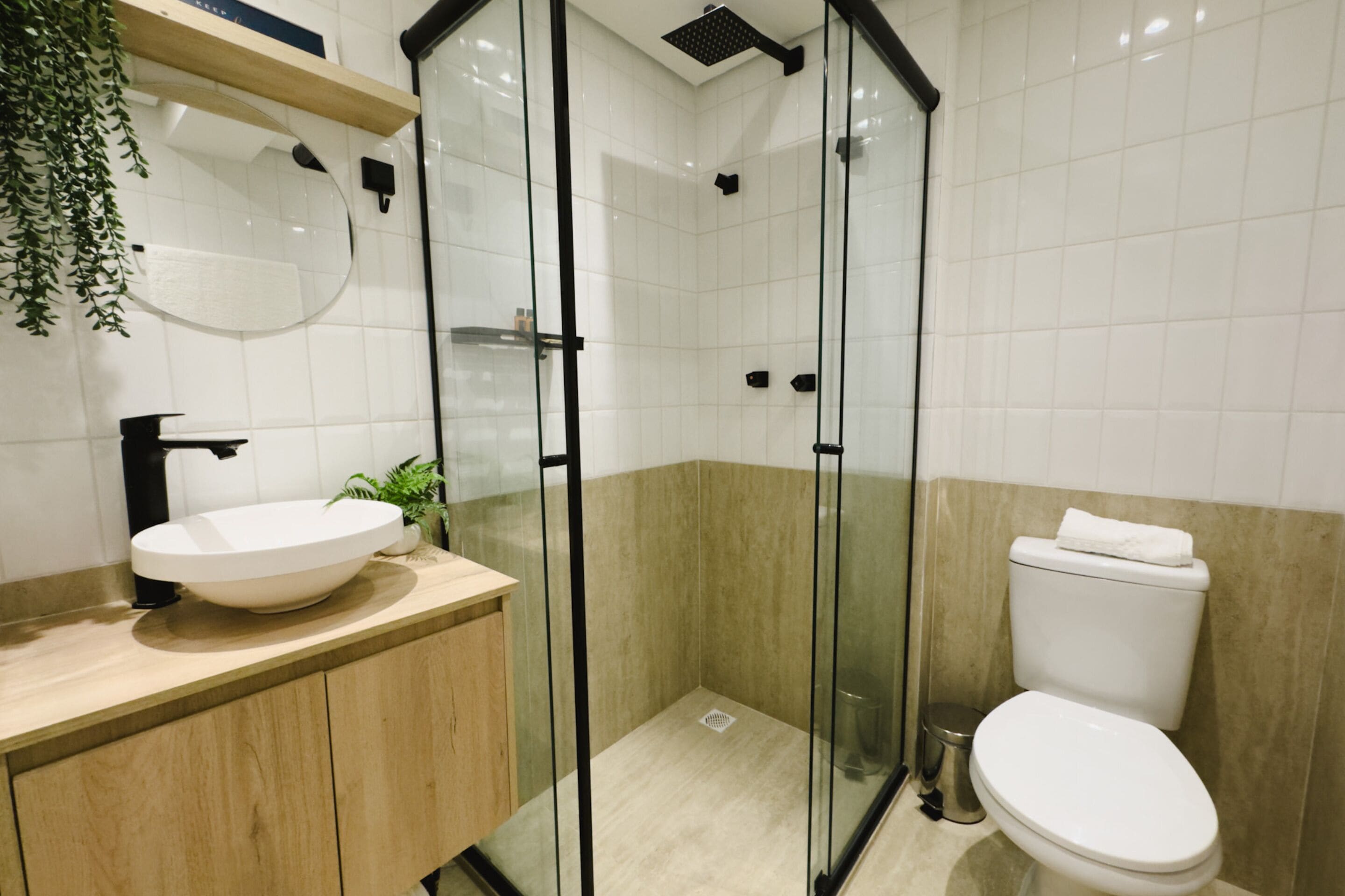 Un baño moderno con ducha envuelta en vidrio, un lavamanos blanco y un inodoro.