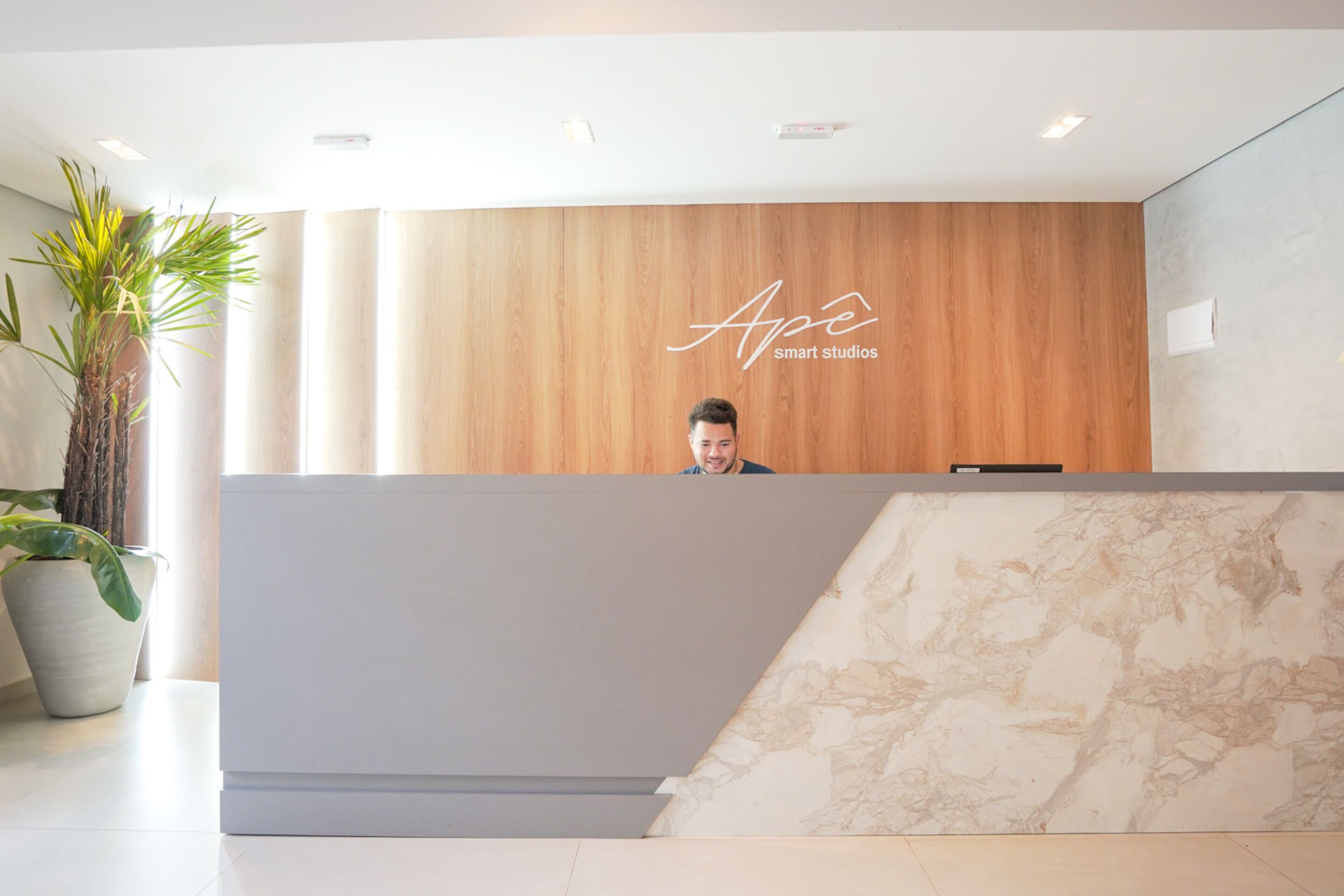 A reception desk with a wooden panel and a marble accent wall.