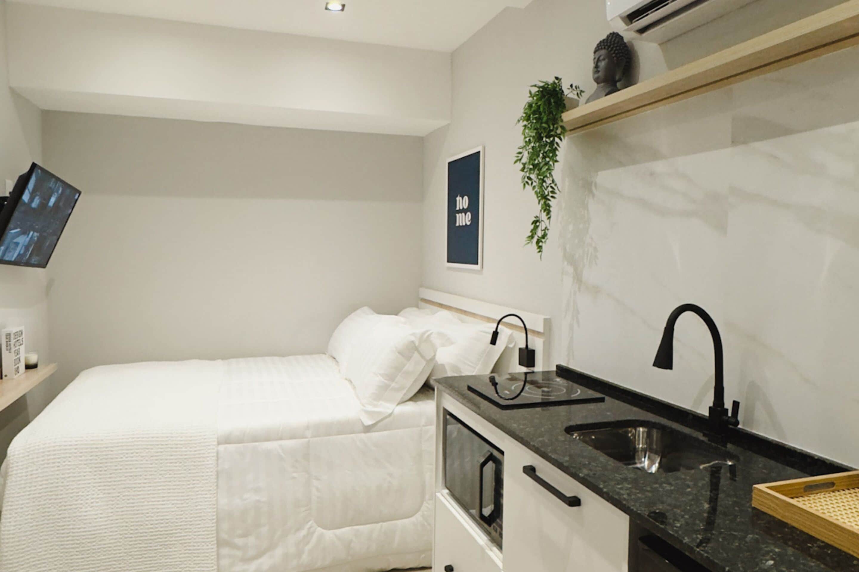 A modern bedroom with a bed, bedside table, and a wall-mounted TV.