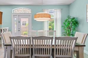 A dining area with a table and chairs, a hanging light fixture, and a potted plant.