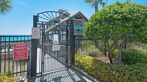 A gated entrance to a private property with a sign indicating no tents allowed on the beach and no lifeguard on duty.
