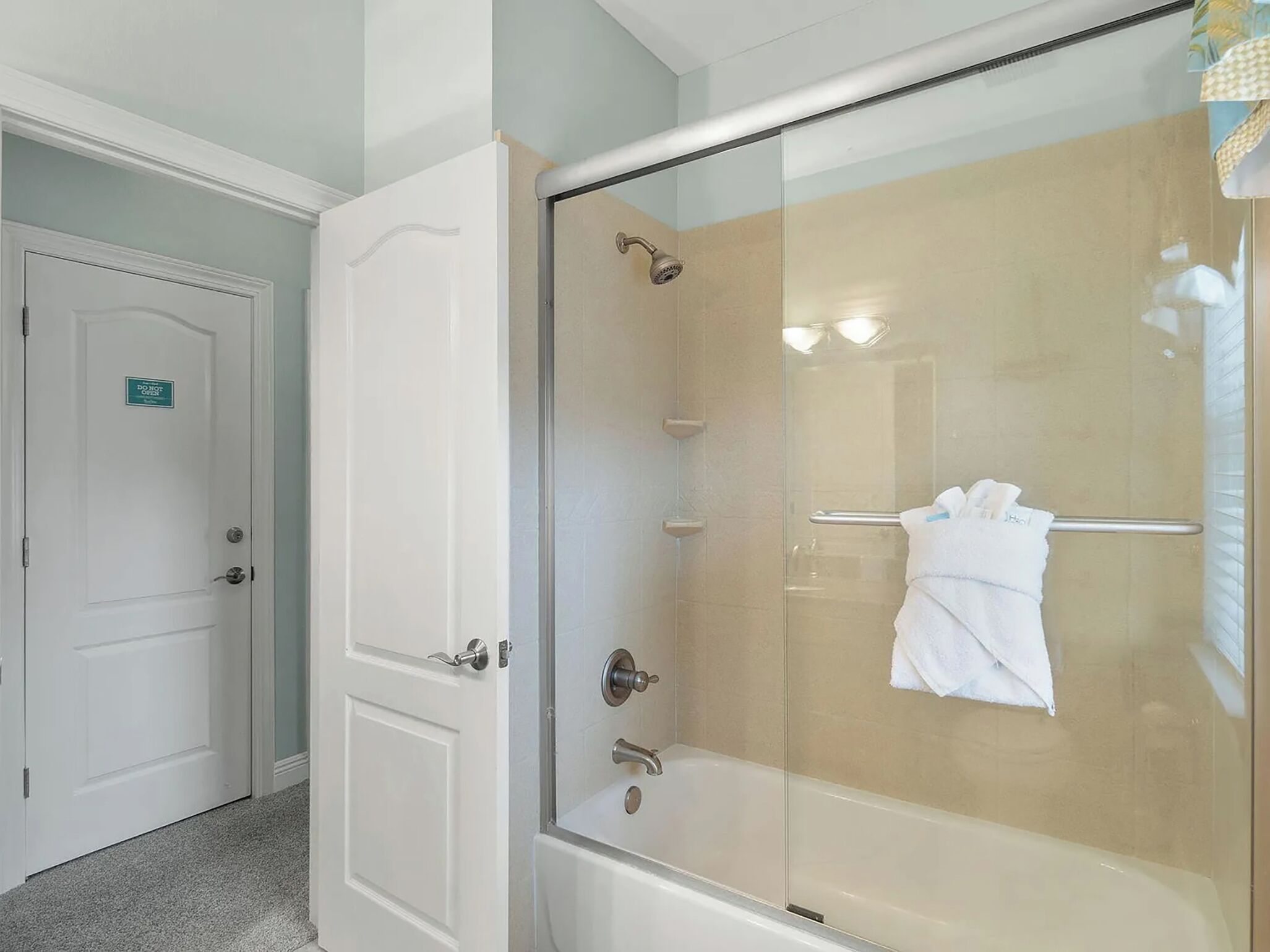 A glass-enclosed shower with a white towel hanging on the door handle.