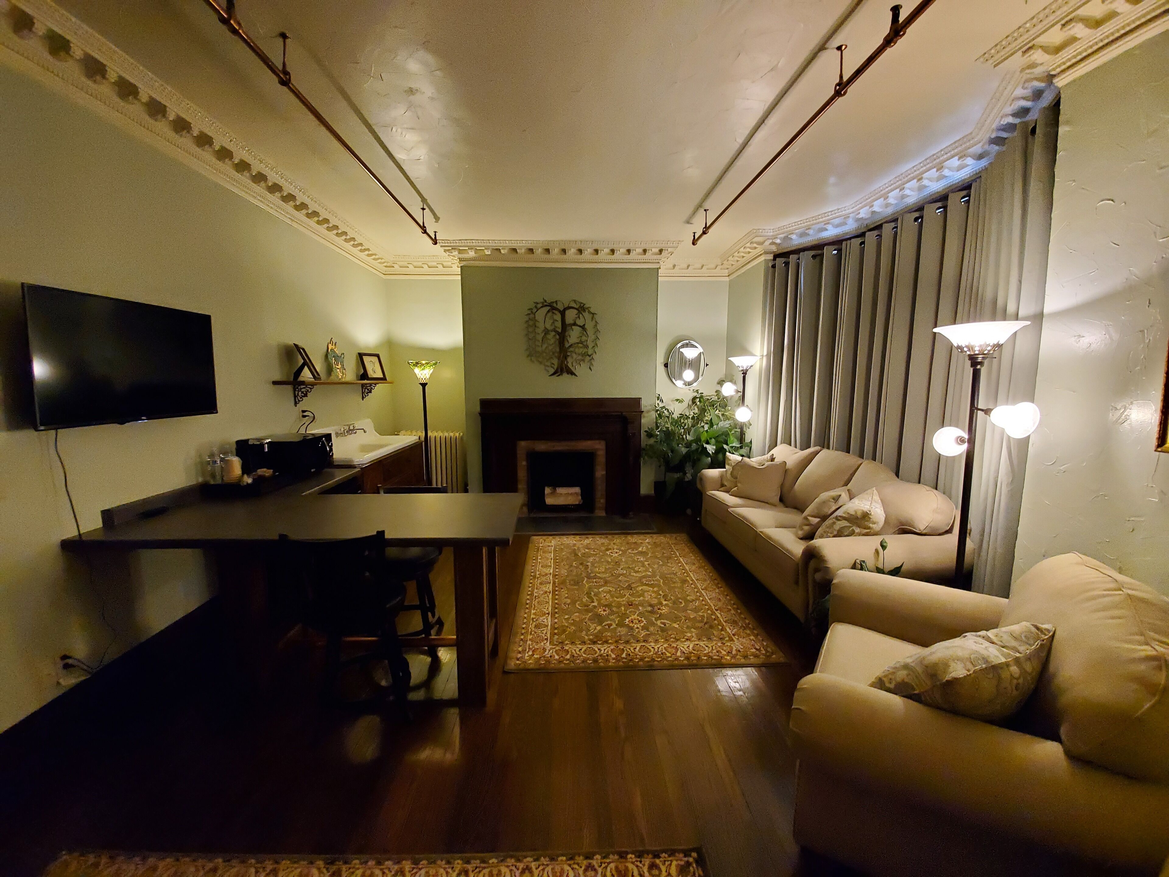 Una sala de estar con televisión de pantalla plana, chimenea, sofá, mesa de centro y comedor con sillas.