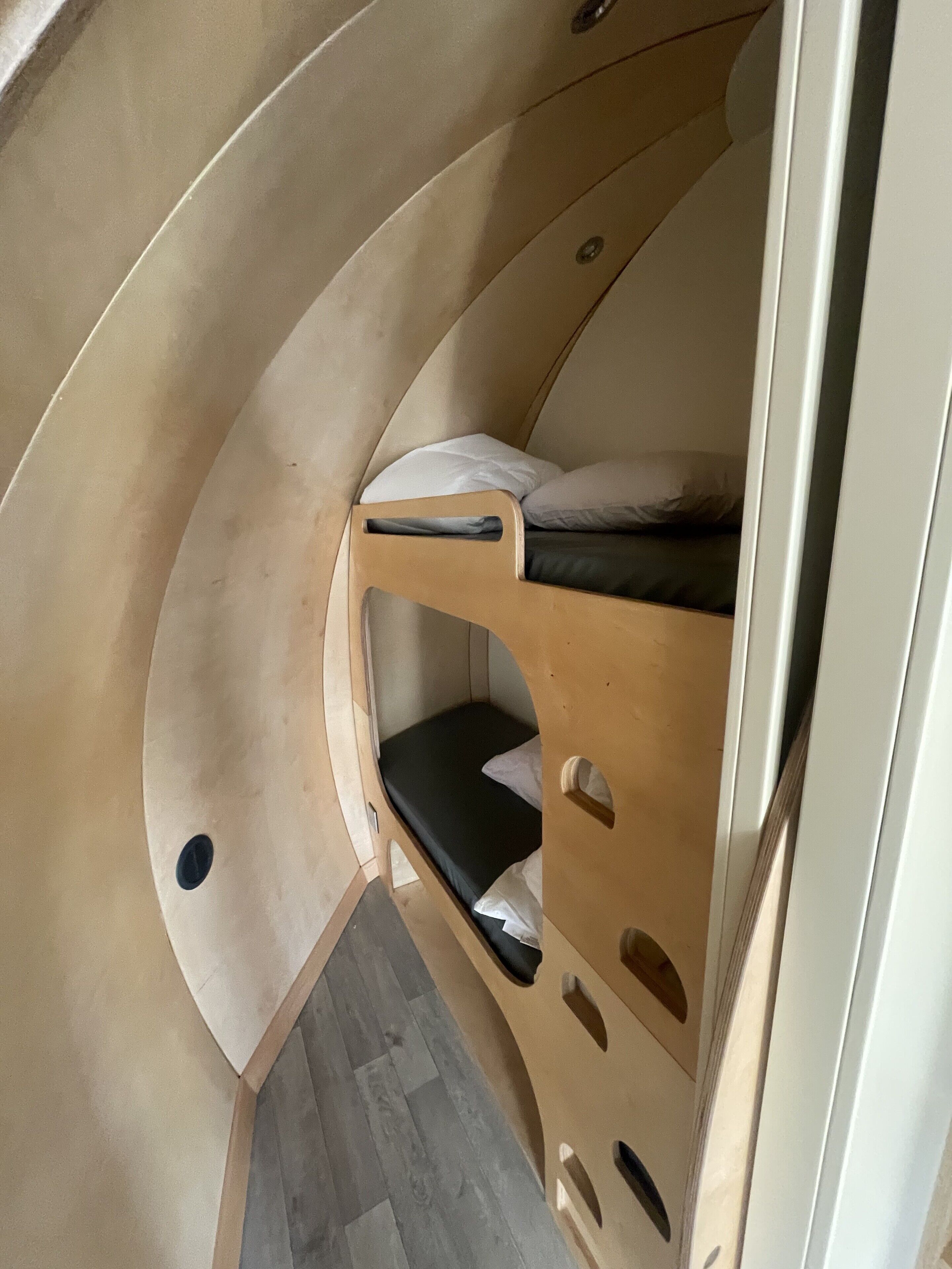 A compact, curved room with a bunk bed and a small seating area.