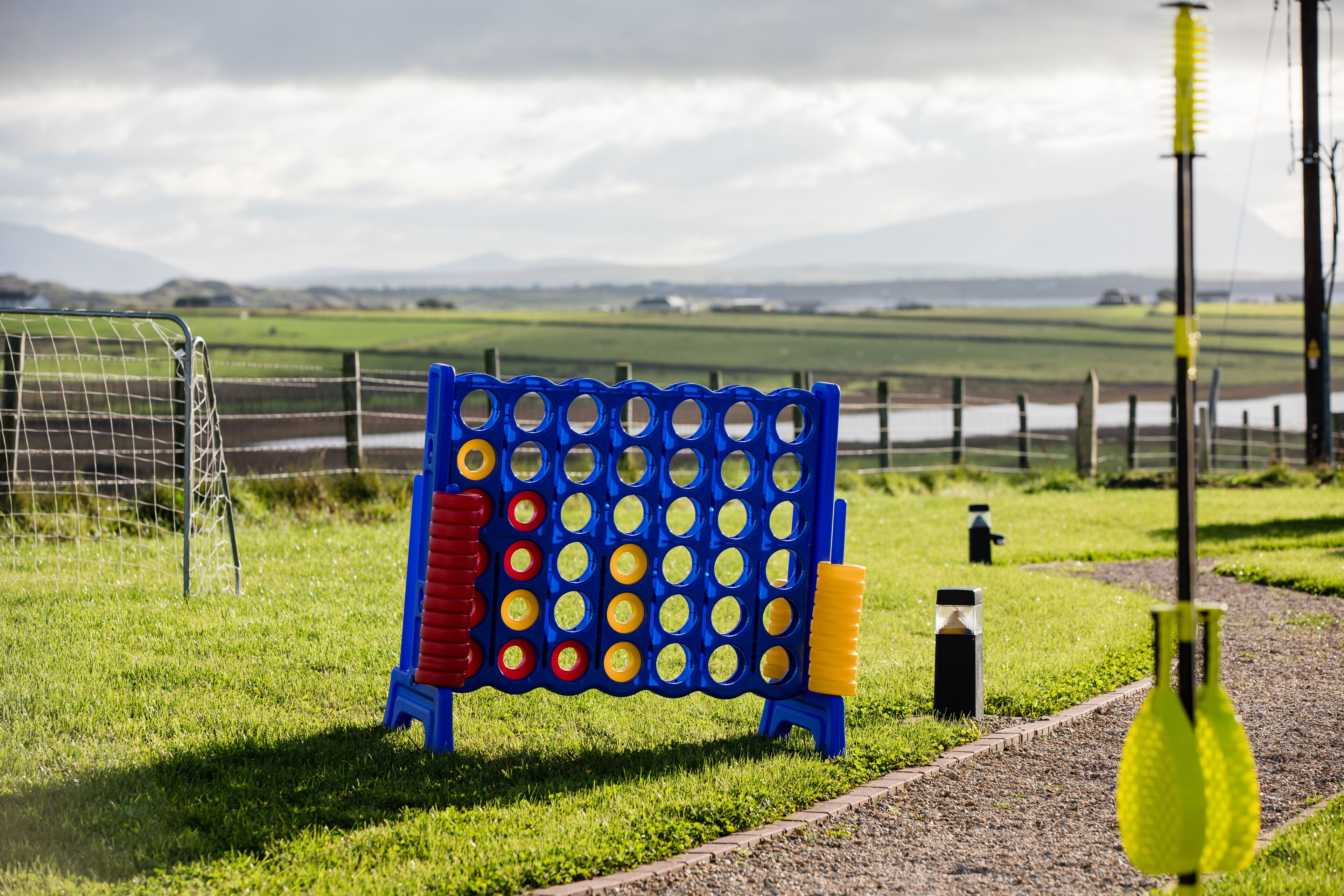Un tablero azul y amarillo con una valla metálica y un campo de césped al fondo.
