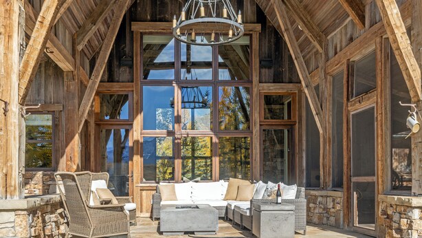A rustic wooden interior with a stone fireplace, large windows, and a stone floor. - Mountain House by Exceptional Stays (Mountain Village)