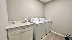 A laundry area with a washing machine, dryer, and Tide detergent on a counter.