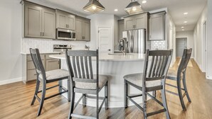 A modern kitchen with a central island, stainless steel appliances, and a dining area with wooden chairs. - Good Vibes Only in the Stillwater at Bridges Bay Resort (Arnolds Park)