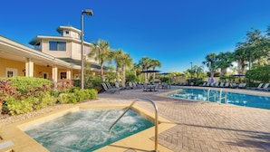 A pool area with a hot tub, lounge chairs, and a building with a unique architectural design. - 2 Mi to Animal Kingdom: Kissimmee Resort Condo! (Kissimmee)
