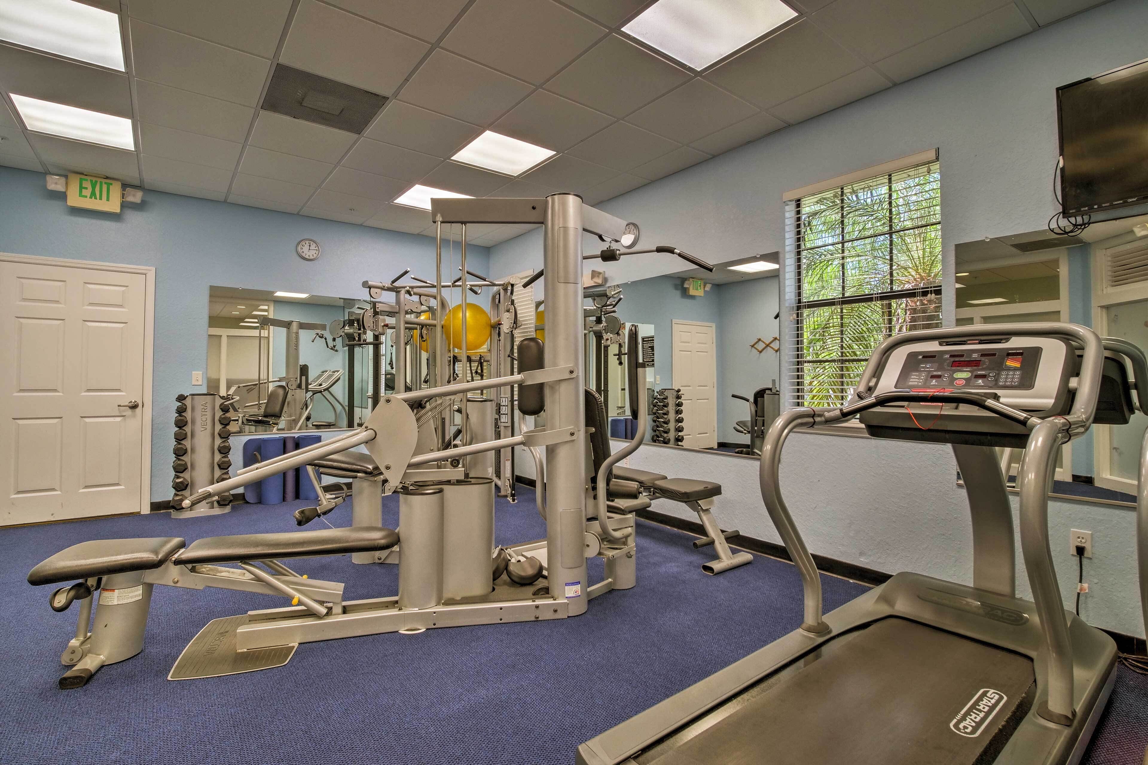 A gym with exercise equipment, a treadmill, and a blue carpeted floor.
