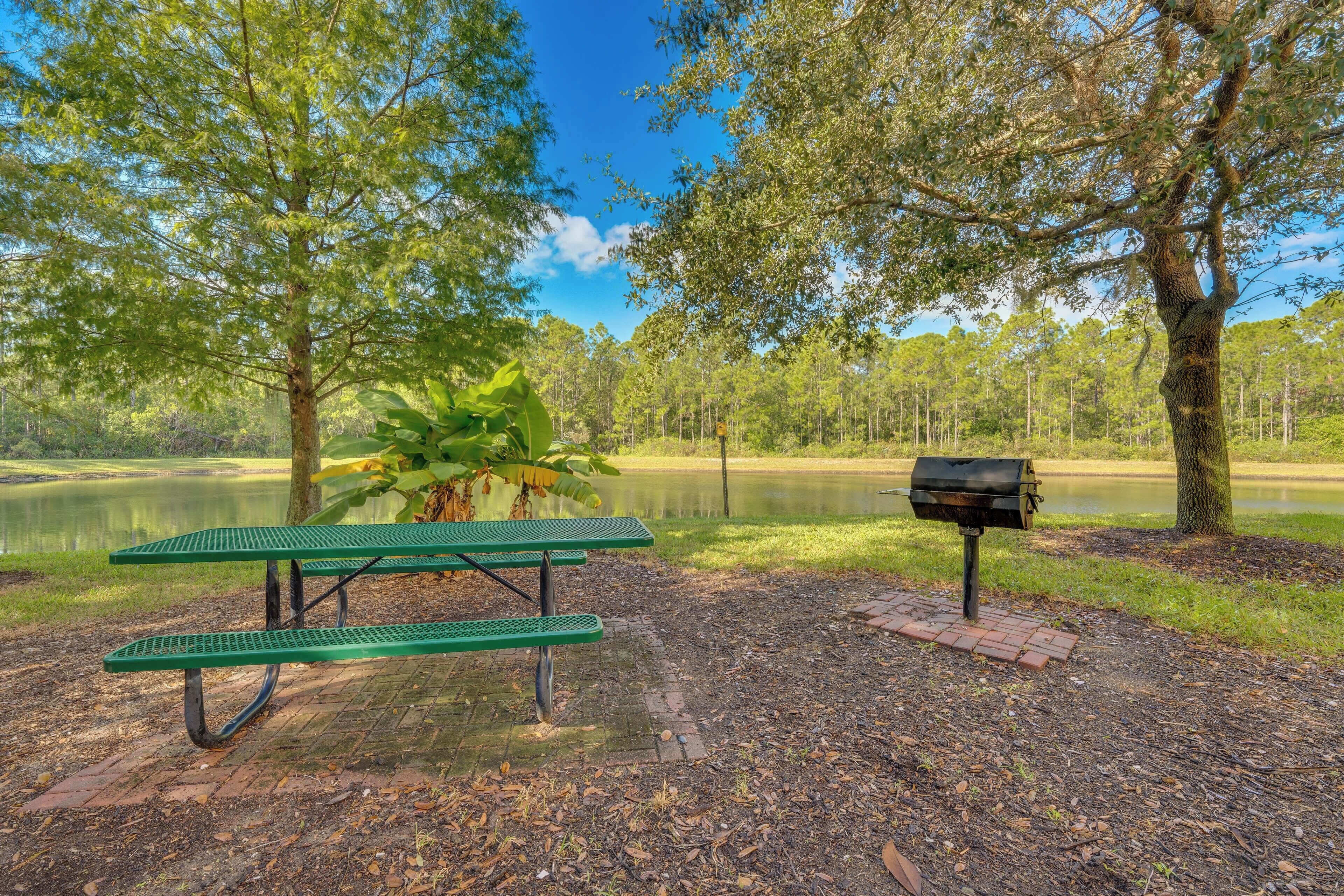 Una mesa de picnic y un buzón en un parque con un estanque y árboles.