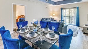 A dining area with a glass table, blue chairs, and a blue sofa in the background. - 2 Mi to Animal Kingdom: Kissimmee Resort Condo! (Kissimmee)