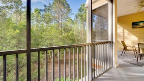 A balcony with a view of a forest, a ceiling fan, and a painting on the wall. - 2 Mi to Animal Kingdom: Kissimmee Resort Condo! (Kissimmee)