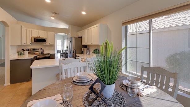 A modern kitchen with white cabinetry, a central island, and a dining area with a table set for two. - Golf Course View! Dog-friendly Retreat in Glendale (Glendale)