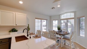 A kitchen with white cabinets, a marble countertop, and a dining area with white chairs and a table. - Golf Course View! Dog-friendly Retreat in Glendale (Glendale)