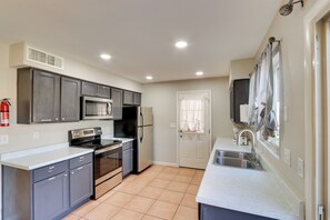 A modern kitchen with grey cabinets, stainless steel appliances, a white countertop, and a tiled floor. - Pool, Game Room! Golfer's Paradise in Mesa (Mesa)