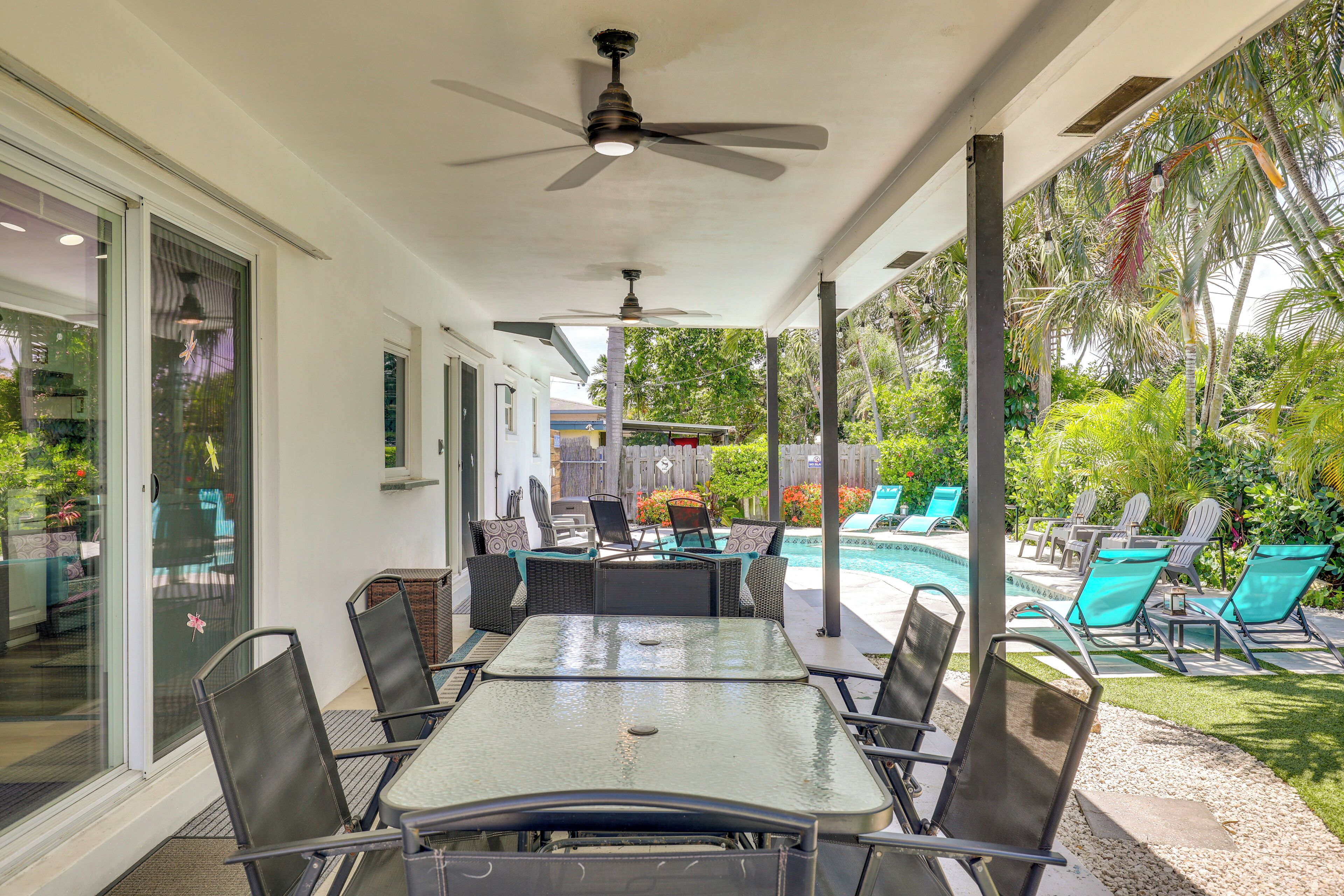 Une terrasse couverte avec une piscine, du mobilier d’extérieur et un ventilateur de plafond.