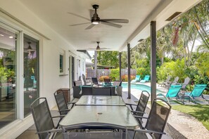 Une terrasse couverte avec une piscine, du mobilier d’extérieur et un ventilateur de plafond.