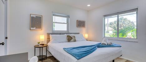 A bedroom with a bed, bedside tables, a chair, and artwork on the walls.