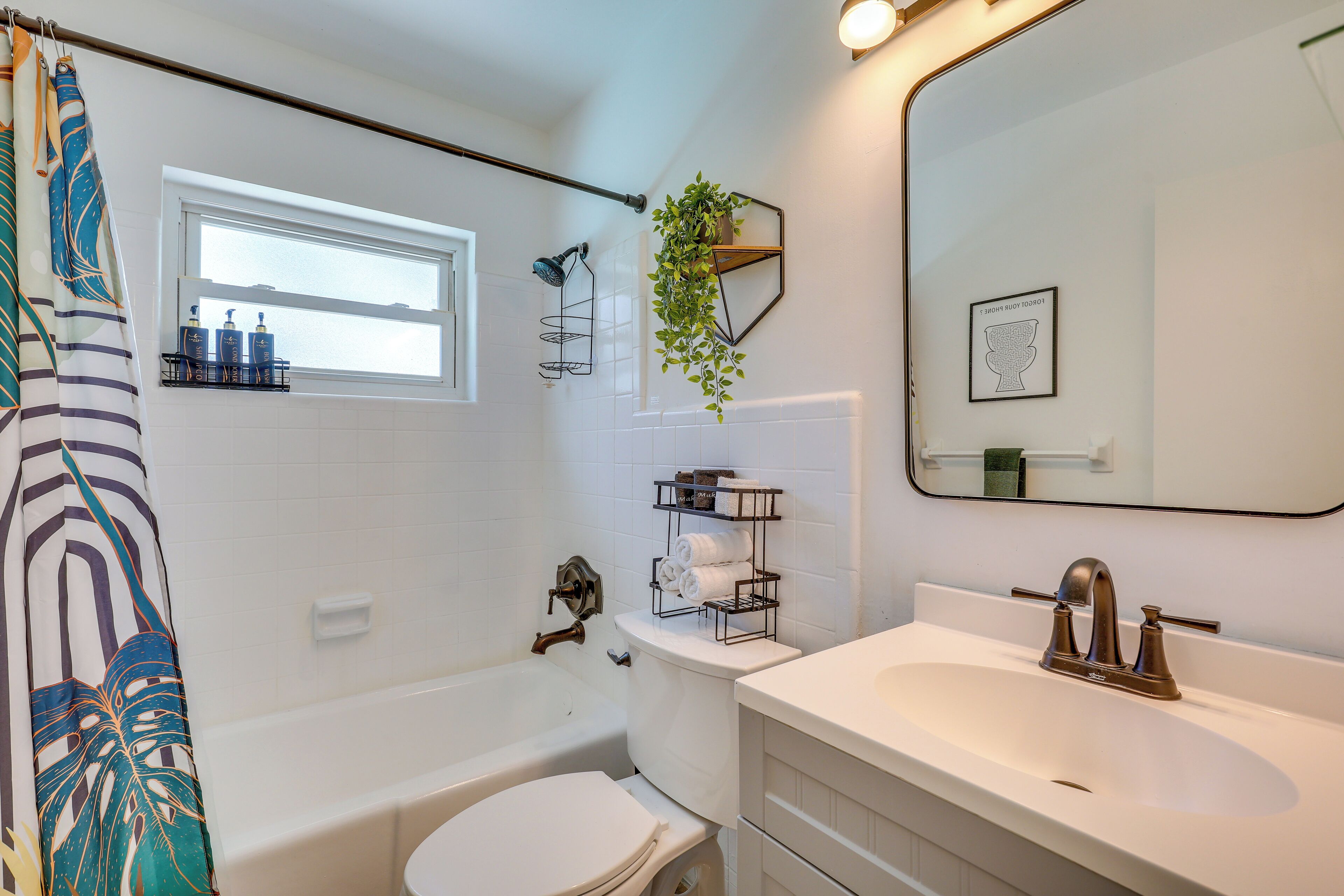 A bathroom with a bathtub, toilet, sink, and a window.