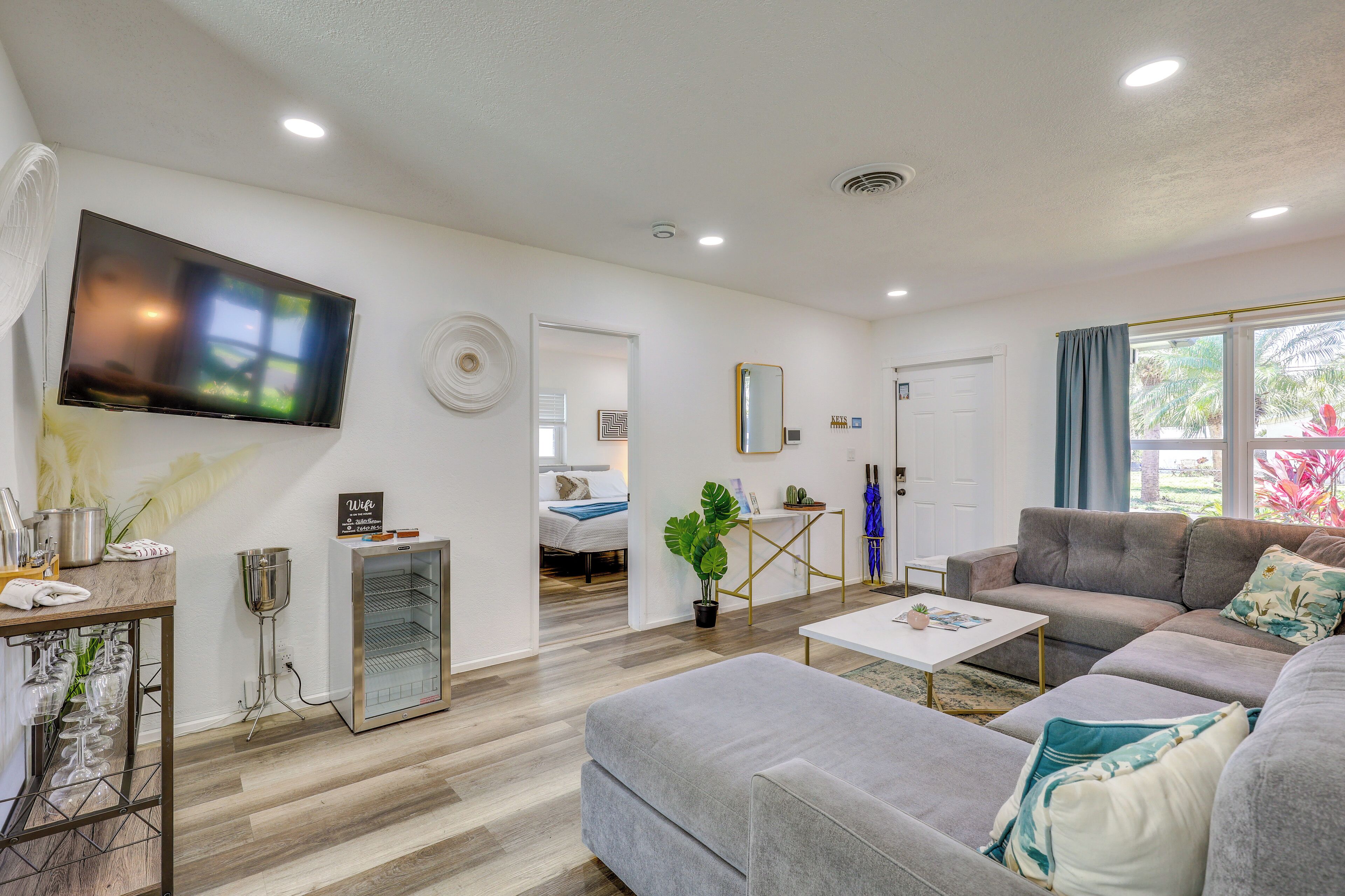 A modern living room with a flat-screen TV, a sofa, a coffee table, and a dining area with a glass-top table.