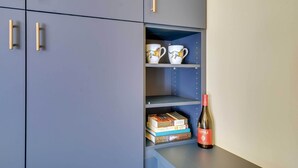 A blue cabinet with gold handles, containing books and a wine bottle. - Unique Grand Junction Guest Suite w/ Gas Fire Pit! (Grand Junction)