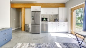 A modern kitchen with stainless steel appliances, white cabinetry, and a wooden ceiling beam. - Unique Grand Junction Guest Suite w/ Gas Fire Pit! (Grand Junction)