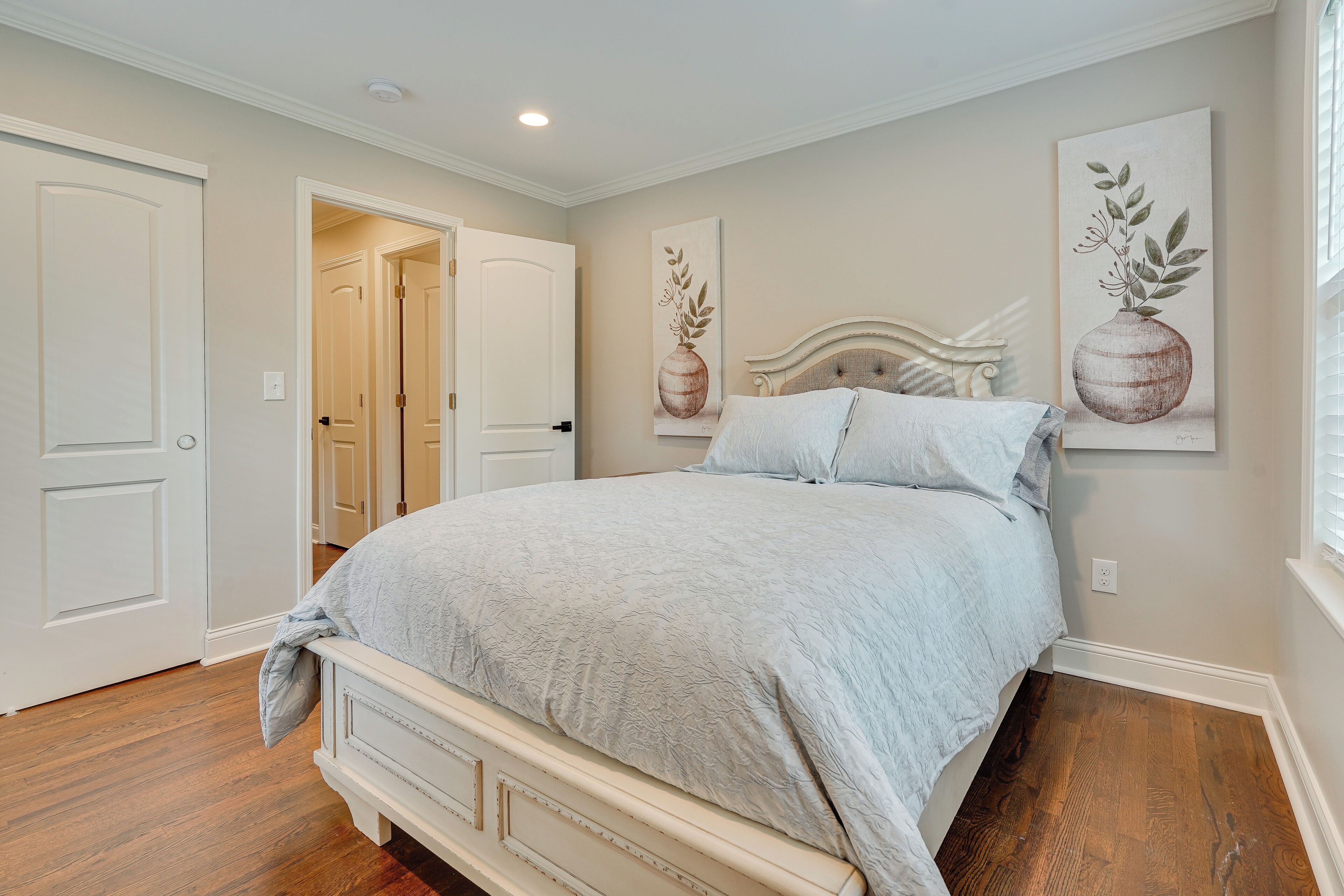 A bedroom with a bed, a door, and a painting on the wall.