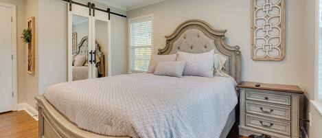 A bedroom with a large bed, a nightstand, a dresser, and a sliding closet door.