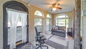 Une pièce avec un mur en pierre, un ventilateur de plafond, un canapé et un bureau avec une lampe.