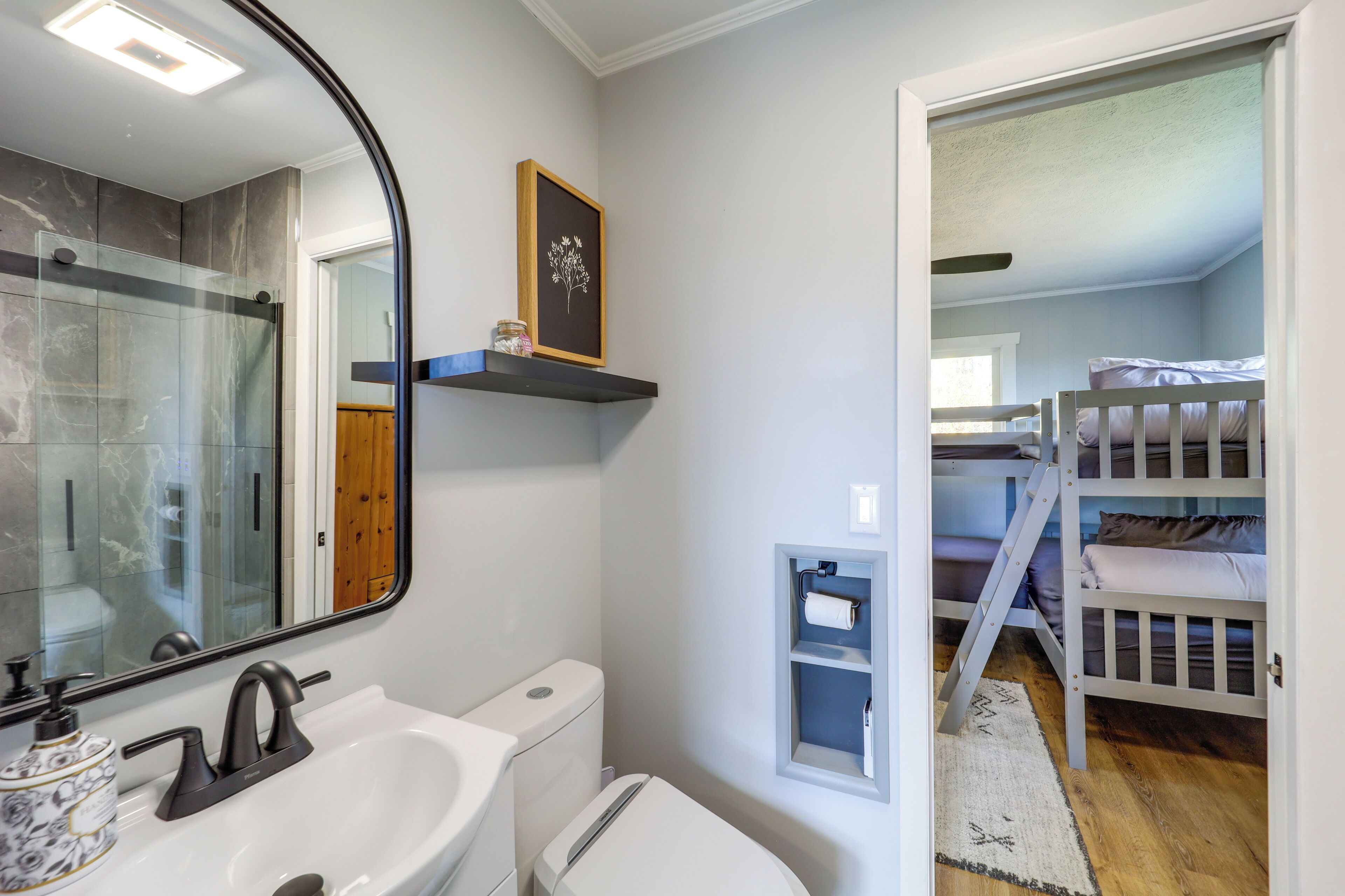 Une salle de bain avec un lavabo blanc, un miroir et un tableau encadré au mur.