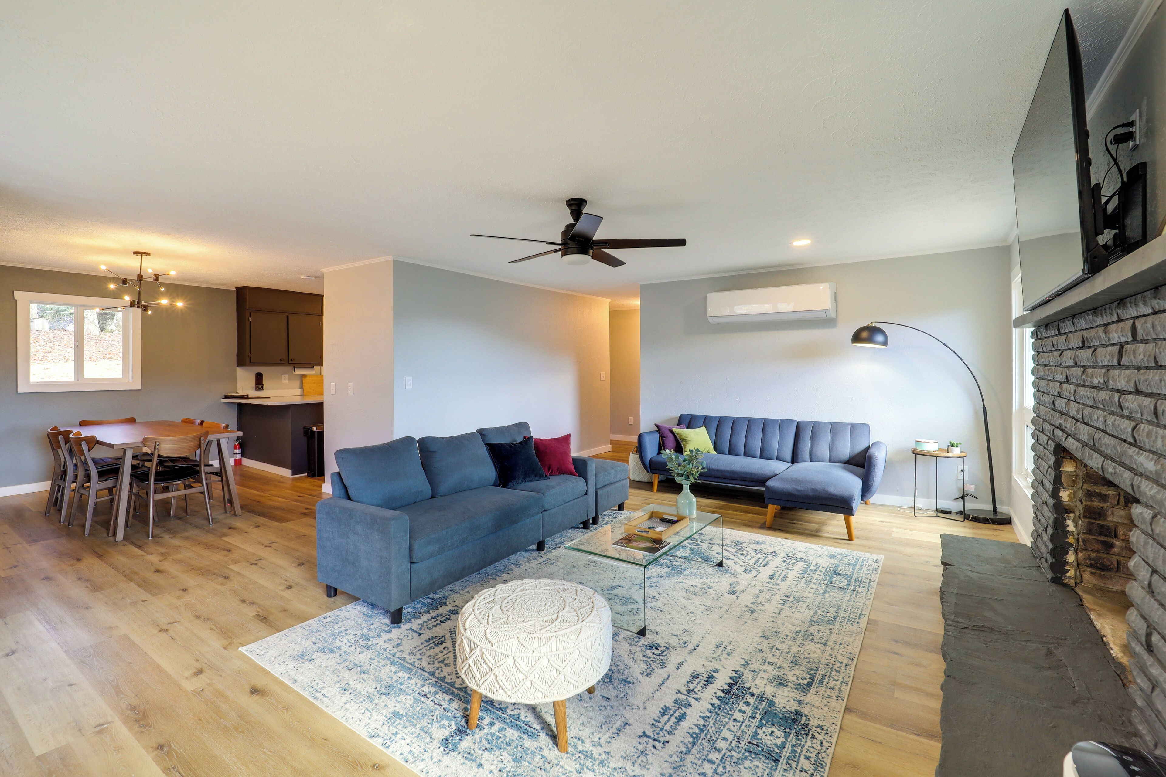 A modern living room with a sofa, coffee table, and ottoman, a dining area with a table and chairs, and a fireplace.