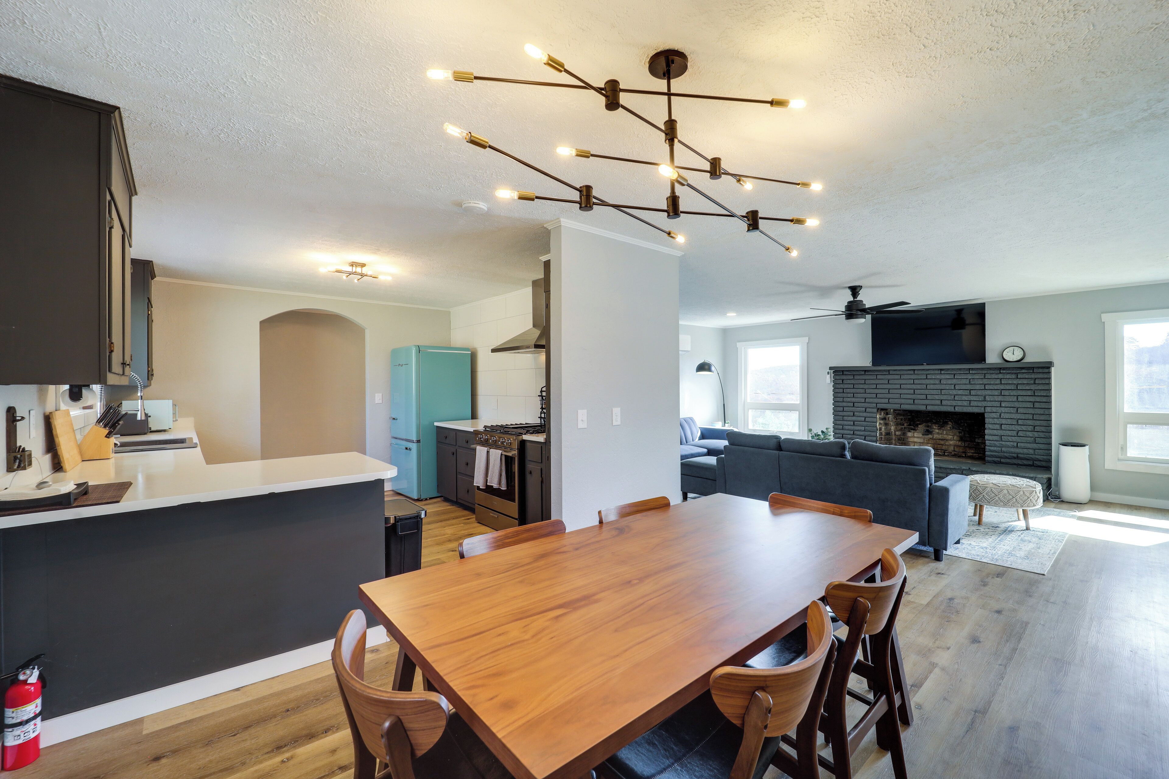 A modern kitchen with a central island, a dining area with a wooden table, and a living room with a fireplace.