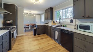 A modern kitchen with dark cabinets, a stainless steel range, and a dishwasher. - Pet-friendly Boone Home w/ Scenic Mountain Views! (Boone)
