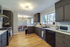 Een moderne keuken met donkere kastjes, een RVS fornuis en een vaatwasser.