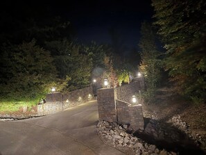 Een verharde oprit die leidt naar een stenen muurpoort met verlichting.