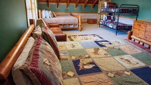 Ein gemütliches Schlafzimmer im Dachgeschoss mit einem hölzernen Bett, einem Etagenbett, einer Holzkommode und einer Steude mit verschiedenen Mustern.