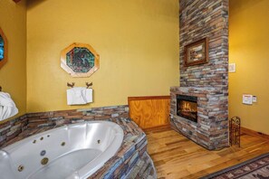A bathroom with a stone fireplace, a bathtub, and a wooden bench.