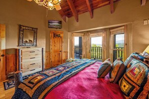 A bedroom with a large bed, wooden dresser, and a balcony with a view. - Majestica: Epic Views, Pool, Pickleball, Hot Tub, Rock Wall, Arcade, Sleeps 28 (Sevier County)