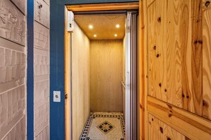 A narrow hallway with a tiled floor leading to a wooden door.