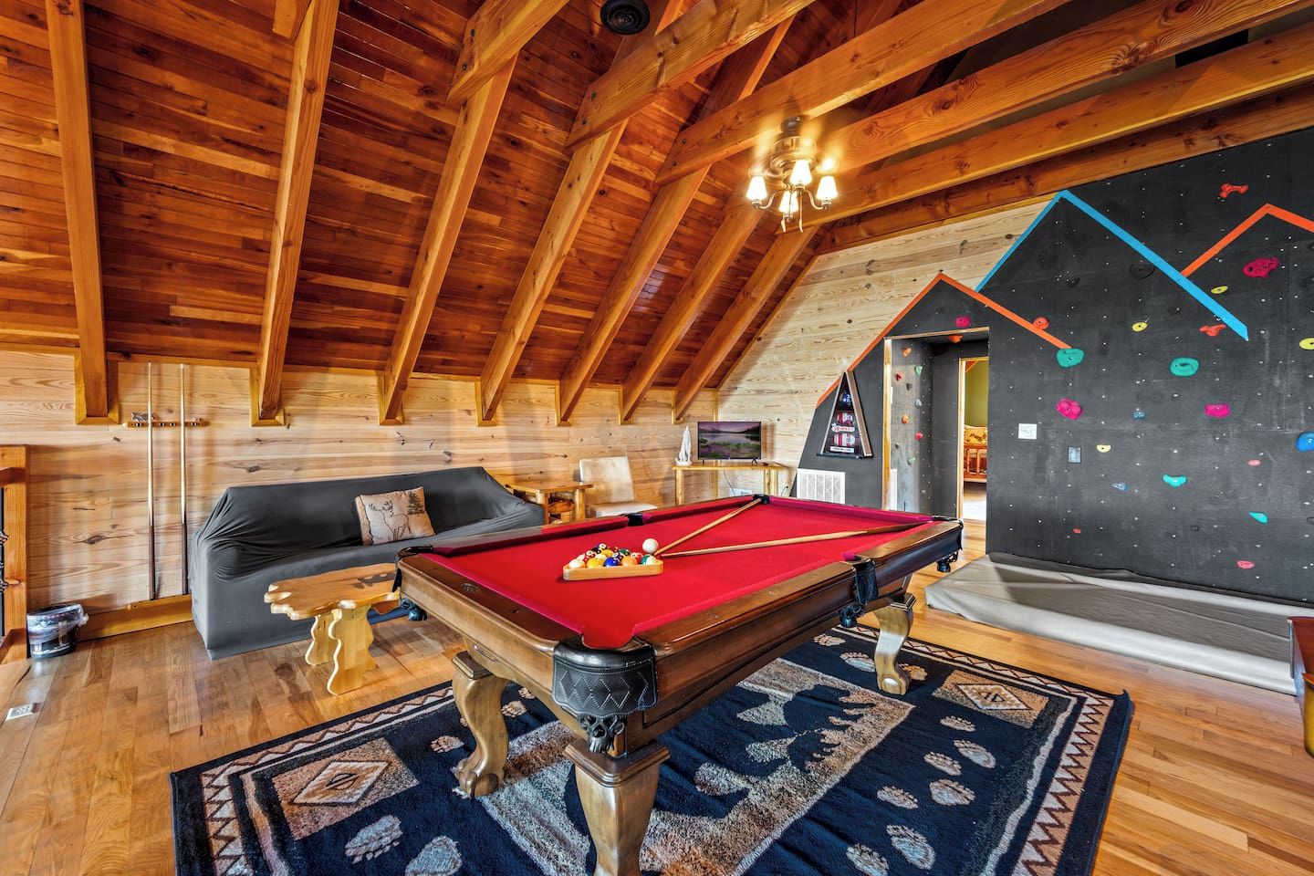 Een gezellige kamer met een pooltafel, een bank en een klimmuur.