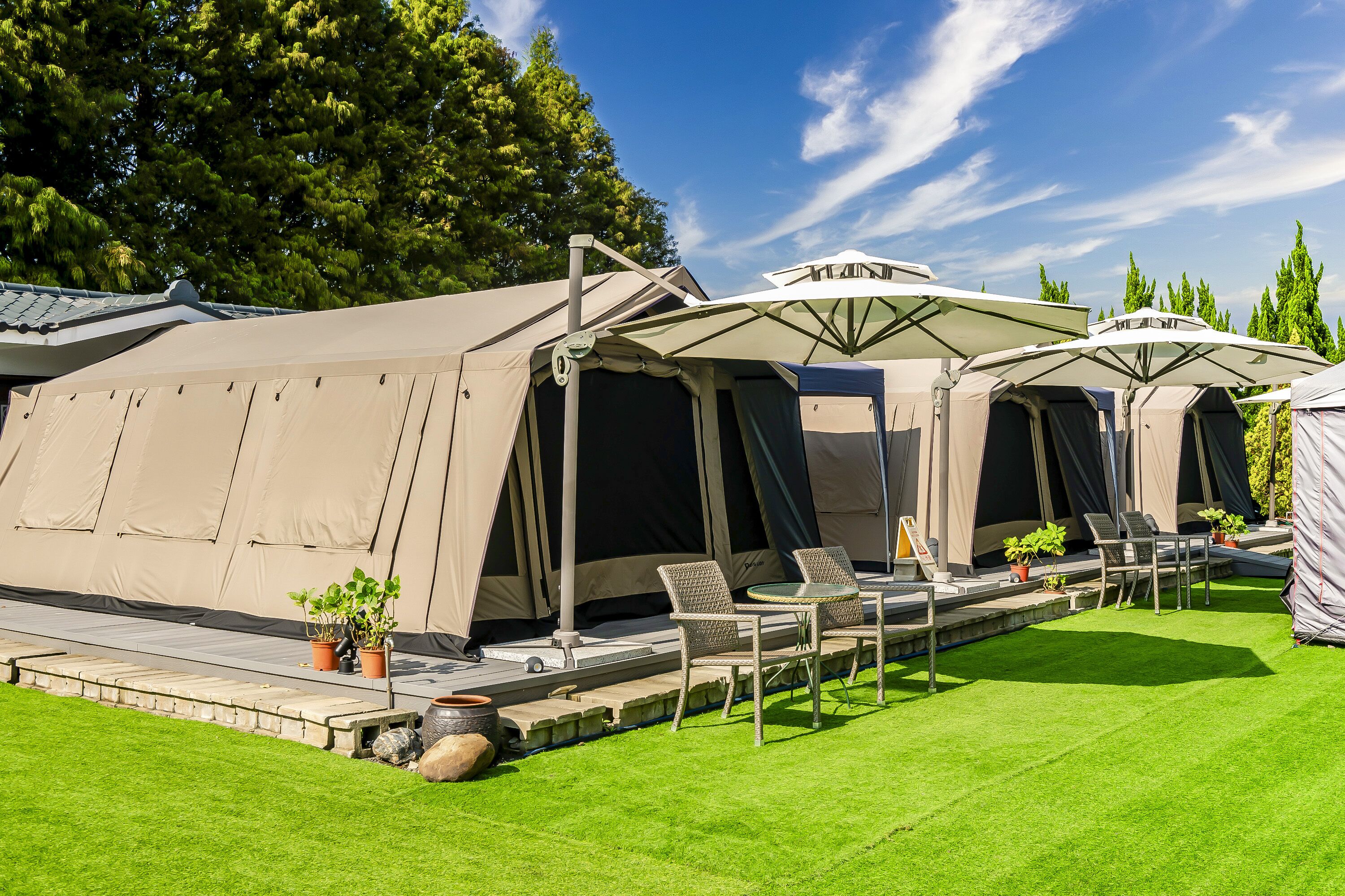 Um camping com várias tendas, área de estar ao ar livre e plantas em vasos.