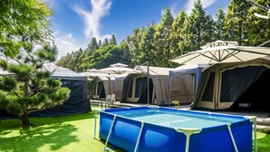 A camping site with multiple tents and a blue inflatable pool. - L.M.S B&B GLAMPING (Gongguan)