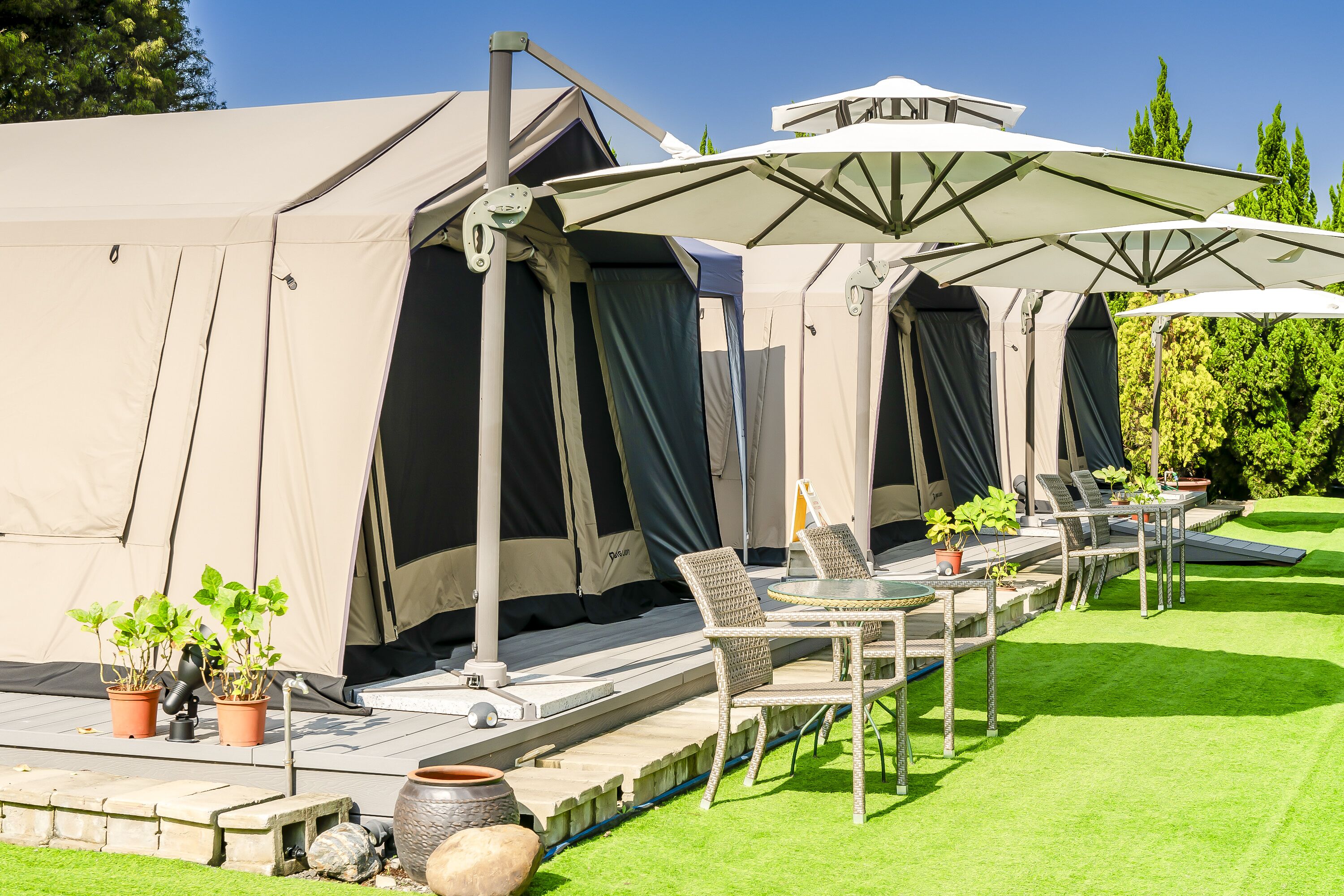 En campingplads med flere telte, udendørs møbler og plantekasser.