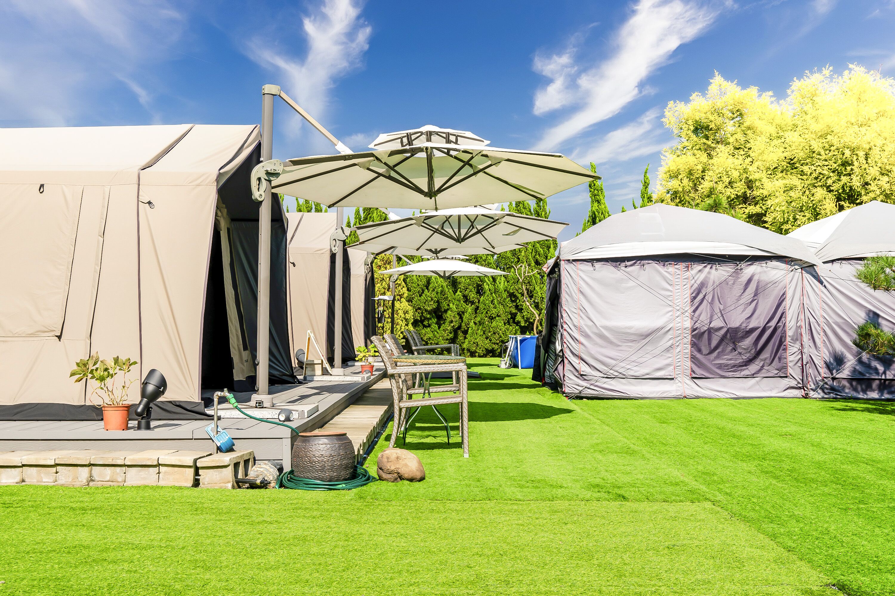 A campsite with tents, a covered seating area, and a well-maintained lawn.