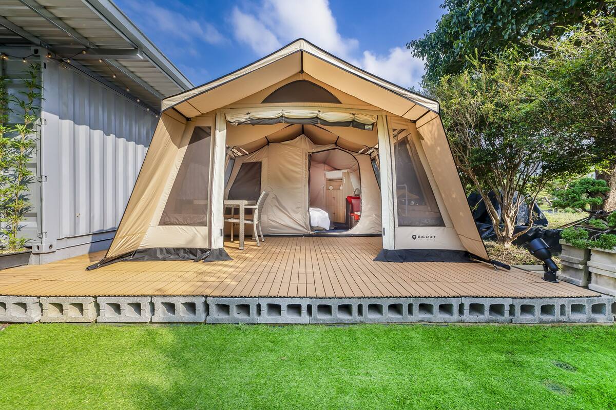 A tented accommodation with a wooden deck, a small table, and a chair.