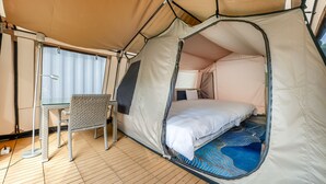 A tent with a bed, a table, and a chair inside. - L.M.S B&B GLAMPING (Gongguan)