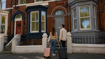 A townhouse with a red door, a bay window, and a white picket fence.