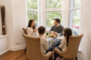 Una familia cenando en una mesa con vistas al exterior a través de amplias ventanas.